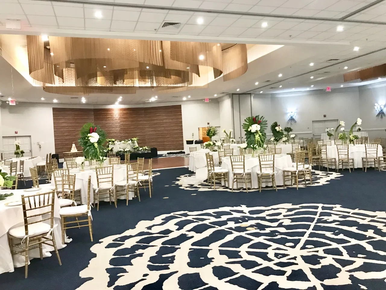 Ballroom reception with tropical floral centerpieces and gold chiavari chairs