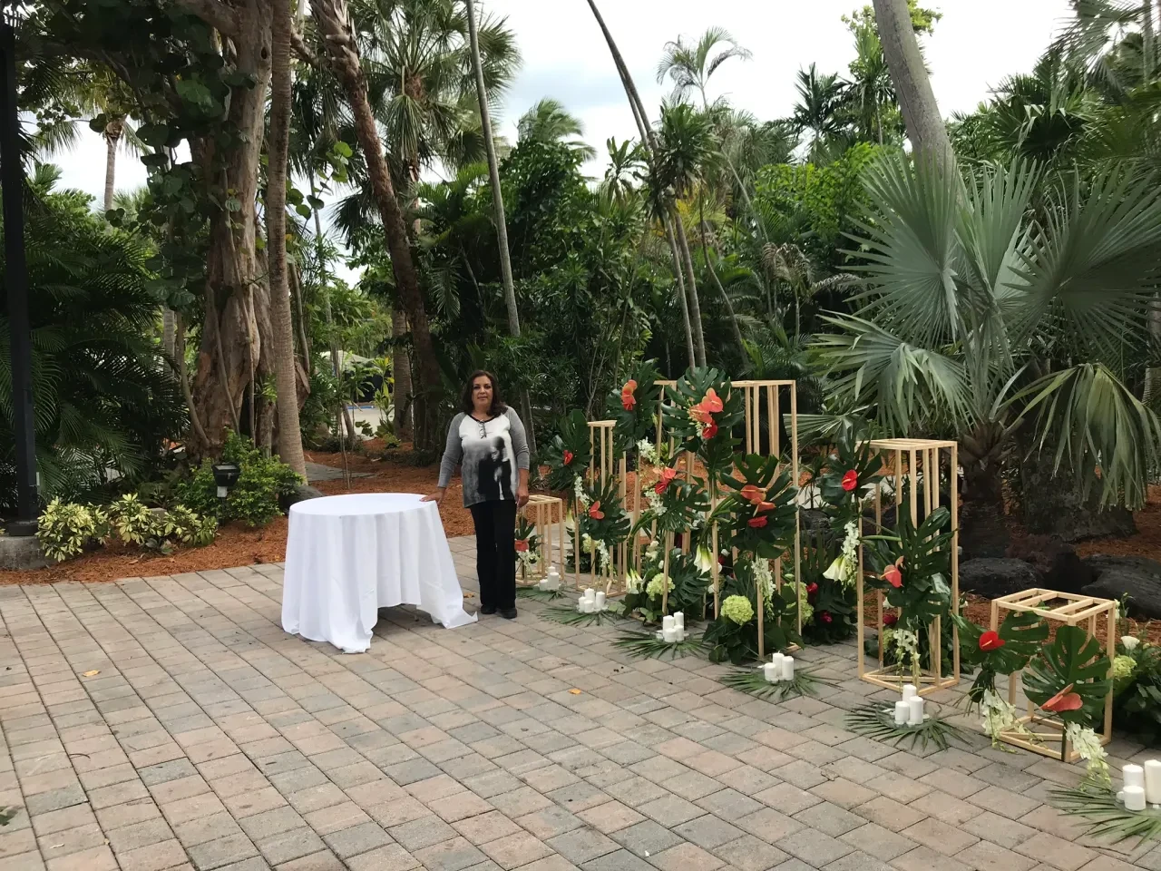 Zuleima standing beside tropical floral altar with gold geometric frames