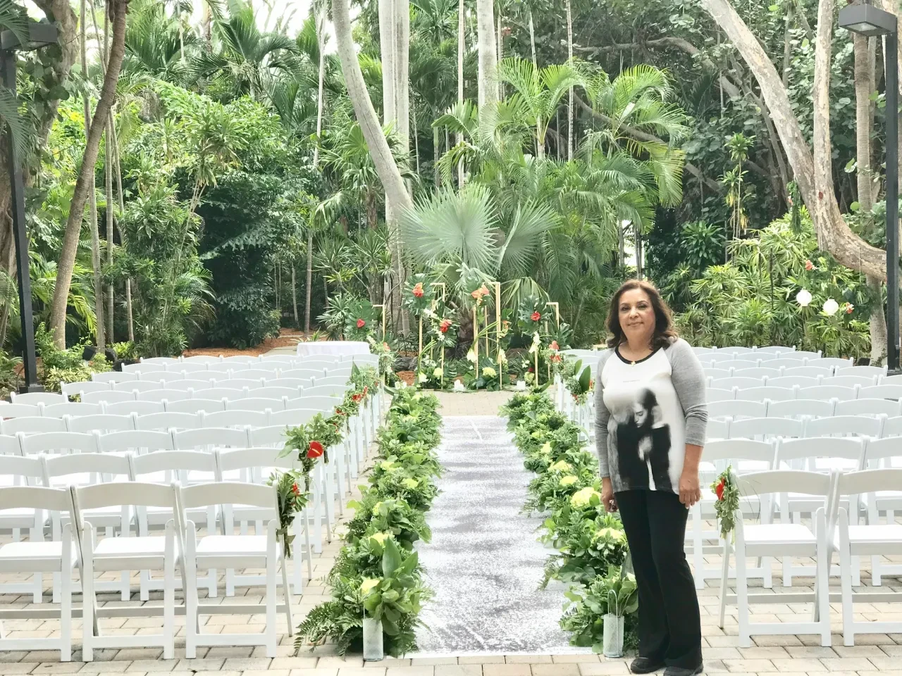 Zuleima standing at ceremony aisle with sequin runner and green decor