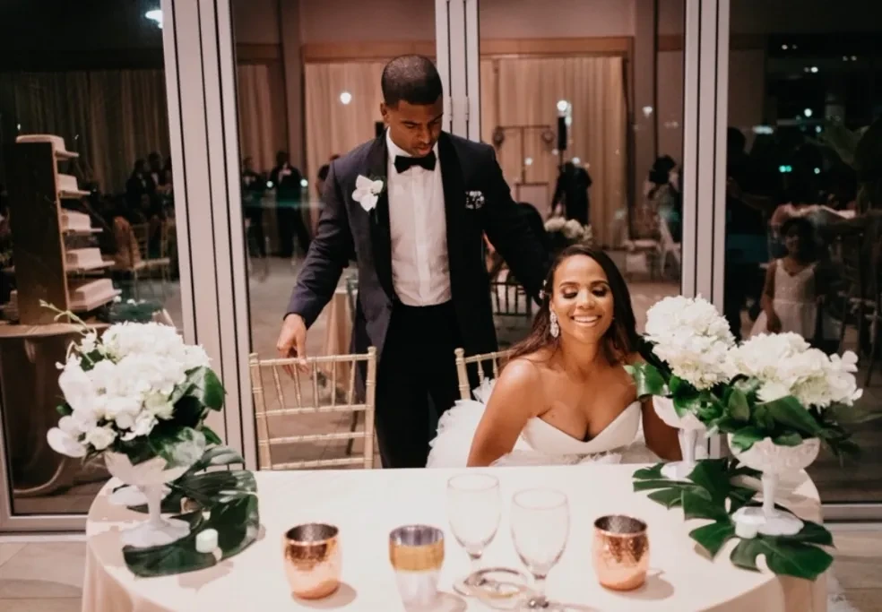 Bride and groom at reception table with white floral arrangements