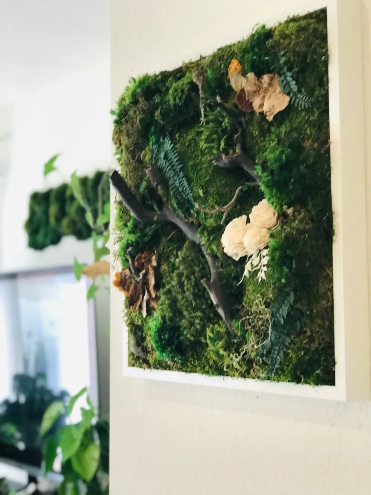 Moss wall art with driftwood branches and dried flowers