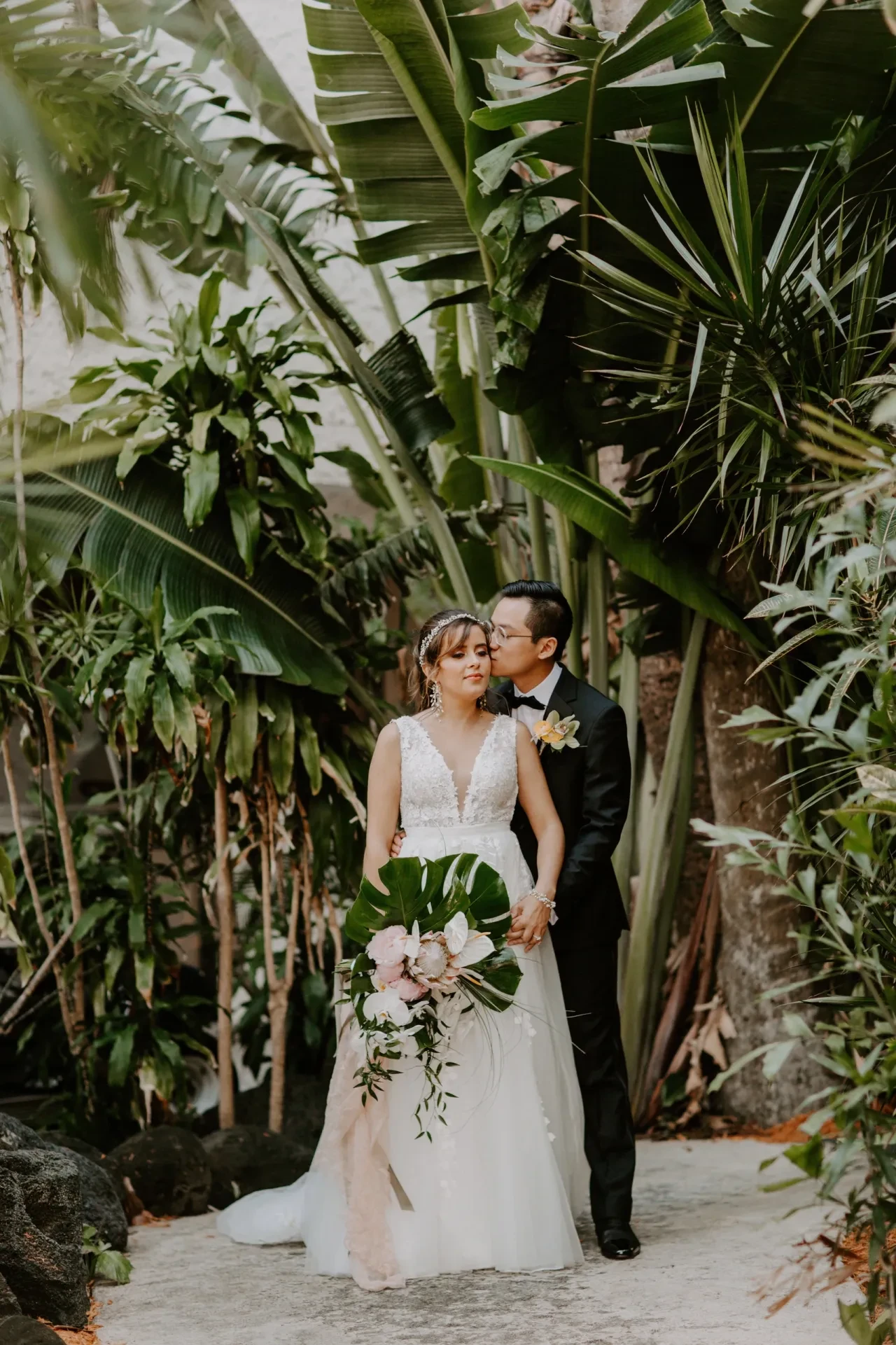 Couple portrait in lush tropical garden with monstera bouquet