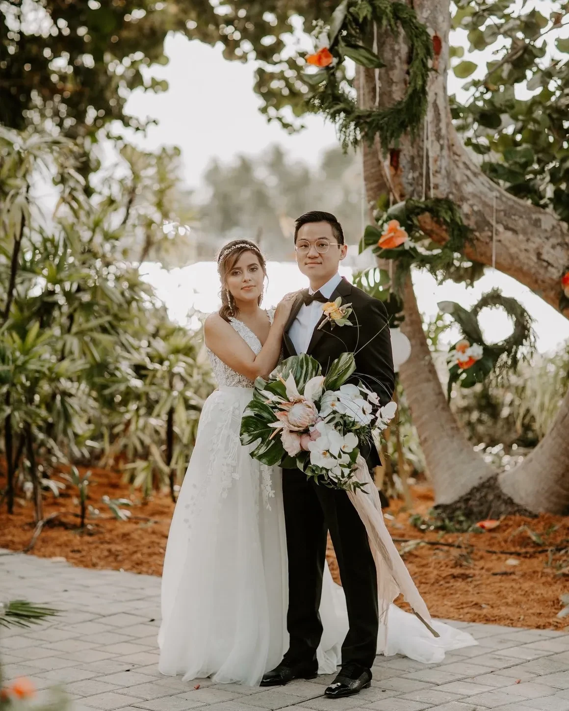 Bride and groom portrait under floral arch with protea bouquet