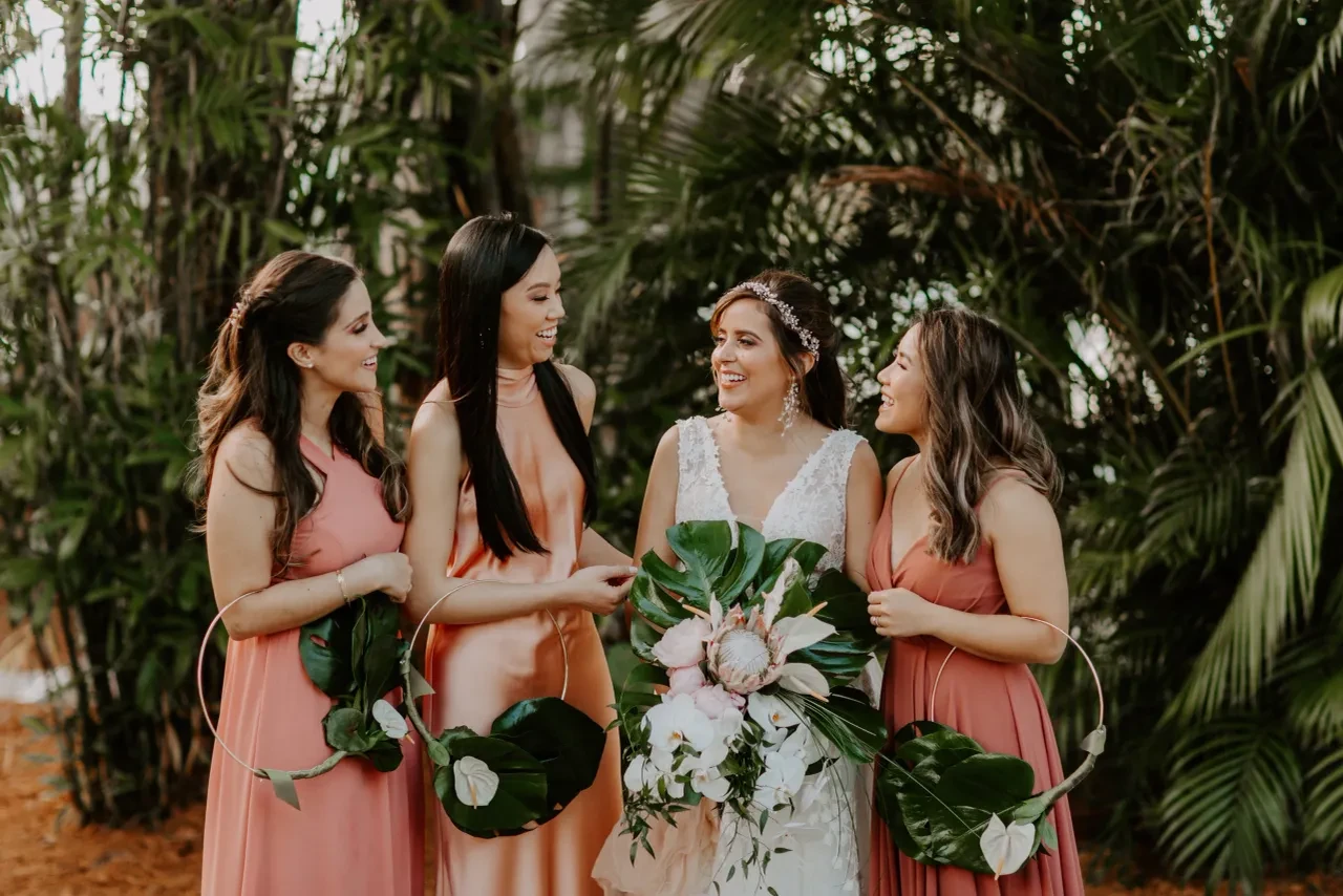 Bride with bridesmaids in coral dresses holding hoop bouquets